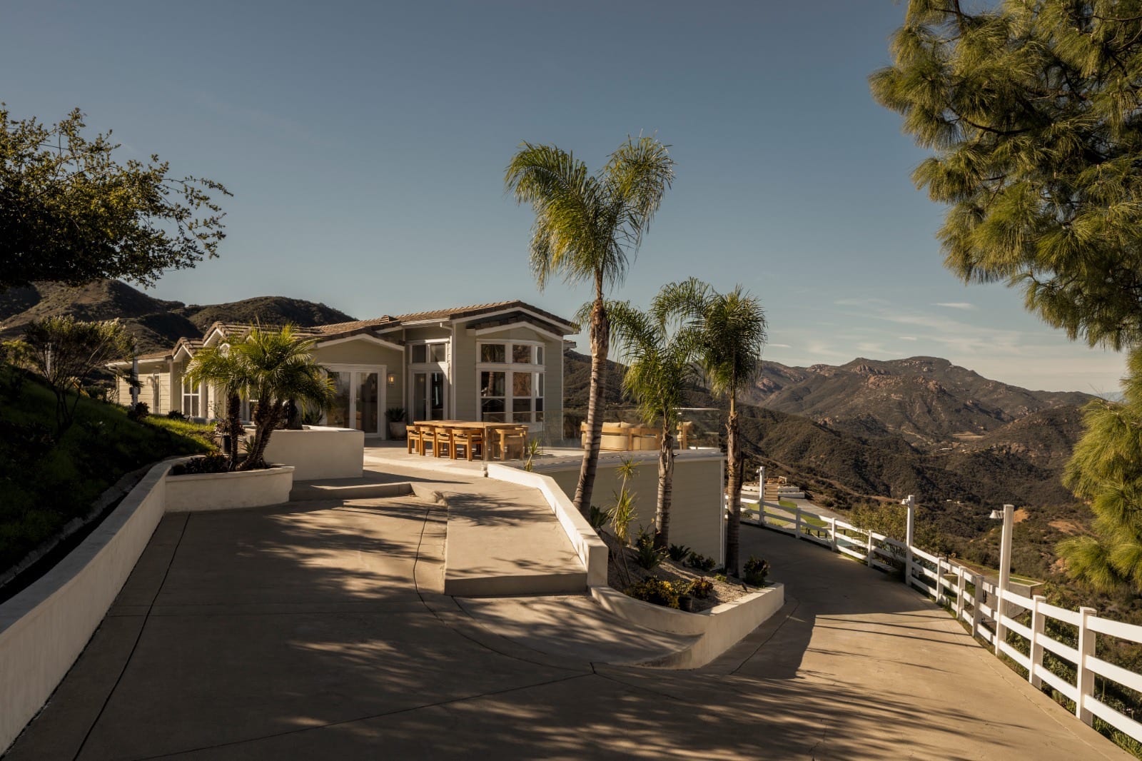 Modern hillside residence with palm-lined terrace at sunset